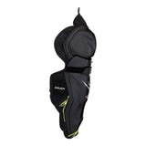 Black hockey shin guard with a dark gray patterned inner panel and small yellow accents, shown from the side on a white background.