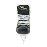 A single Bauer hockey skate boot in black with yellow and white accents, featuring a white blade and silver laces, shown against a plain white background.