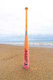 Orange baseball bat with 'TAM' branding on a sandy beach