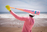 Person holding a large pink bat on a beach
