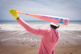 Person holding a large pink bat on a beach