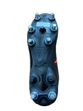 Black soccer cleat with metal studs on a wooden surface