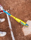 Colorful baseball bat on a dirt field with a player's foot wearing a glove and shoe.