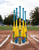 Six yellow and blue baseball bats standing upright on a home plate at a baseball field.