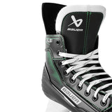 A close-up of a Bauer XLSI ice hockey boot in black, white, and green, showing the lace-up front, ankle support, and Bauer branding.