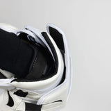 Close-up of a white sneaker with black accents on a light gray background