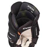 Close-up of a CCM hockey glove showing the inner side with black and dark gray padded sections, white CCM branding, and a small orange accent tab on a white background.