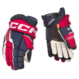 A pair of CCM hockey gloves shown from both the back and palm sides on a plain white background. The gloves feature a color-blocked design of navy blue, red, and off-white, with the CCM brand logo prominently displayed on the back glove wrist strap.