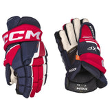 A pair of CCM junior hockey gloves shown from both the front and back views on a solid white background. The gloves feature a color-blocked design of navy blue, red, and white, with the CCM brand name prominently displayed on the wrist strap.