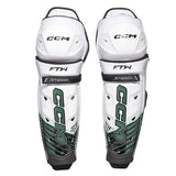 Pair of white hockey shin guards with black and green accents on a white background