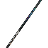 A close-up diagonal view of a CCM Unigriped hockey stick shaft, featuring the CCM logo in metallic gold and the 'UNIGRIPED' text in a metallic iridescent finish that shifts from green to blue to purple, set against a solid white background.