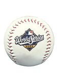 A white baseball with red stitching and a prominent 2025 World Series logo, displayed in front of a metallic trophy on a dark surface.