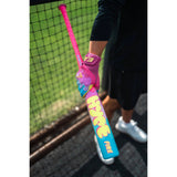 A person in a batting cage holding a bright pink and blue Fierce Fast 26 baseball bat with a pink batting glove.