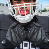 Person wearing a football helmet and protective gear with a blurred background
